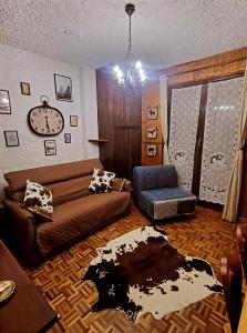a living room with a couch and a clock at CHALET LAVANDA San Giacomo di roburent in San Giacomo