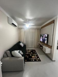sala de estar con sofá y TV de pantalla plana en Apto 11 - Aconchegante - Praia da Enseada - Guarujá/SP, en Guarujá