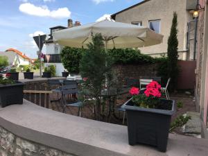 a patio with tables and an umbrella and flowers at Gasthaus da Enzo in Siefersheim