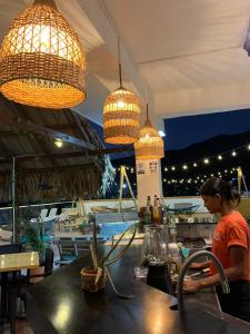 a woman sitting at a table in a restaurant with lights at Hostal Viña del Mar in Taganga