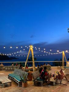 a group of people sitting in chairs on a deck at night at Hostal Viña del Mar in Taganga