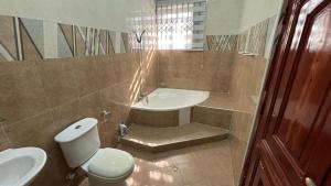 a bathroom with a toilet and a sink and a tub at MatKay 3 bedroom House in Oyibi