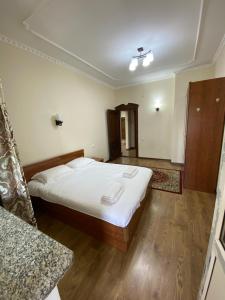 a bedroom with a bed with white sheets and wooden floors at Narke Hostel in Bishkek