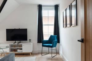a living room with a blue chair and a television at Spacious & Modern Two Bedroom Apartment in Catford, London in Catford