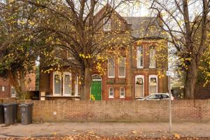 a brick house with a green door on a street at Spacious & Modern Two Bedroom Apartment in Catford, London in Catford
