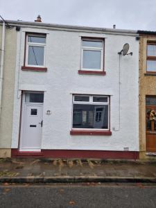 a white house with a white door and windows at 3 bedroom Urban Retreat Near Bike Park Wales in Merthyr Tydfil