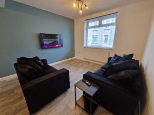 a living room with two chairs and a flat screen tv at 3 bedroom Urban Retreat Near Bike Park Wales in Merthyr Tydfil