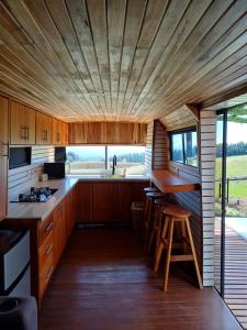 uma cozinha com armários de madeira e uma grande janela em BusHotel Poás con Jacuzzi y Chimenea em Fraijanes