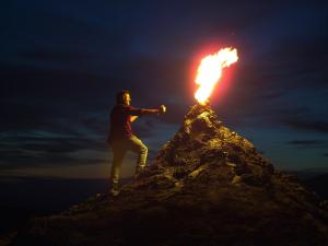 un hombre parado sobre una roca con fuego en Baku "Black Mountain" Guest House, en Sangachal