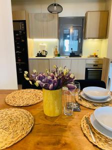 a wooden table with plates and a vase of purple flowers at NEW 2BD APRT with SHARED ROOFTOP POOL E2 in Athens +31 photos