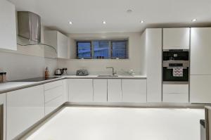 a white kitchen with white cabinets and a sink at Habitacion lujosa en el centro de Londres in London