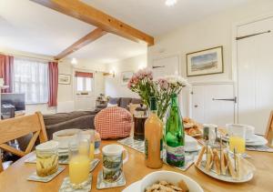 a table with food and flowers in a living room at Wayfarer Cottage in Woodbridge