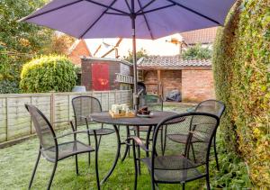 a table and chairs with an umbrella in a yard at Wayfarer Cottage in Woodbridge