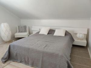 a white bedroom with a bed and a chair at 3 Bedroom Duplex apartment in Helsinki