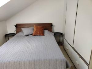 Schlafzimmer mit einem Bett mit orangefarbenem Kissen in der Unterkunft 3 Bedroom Duplex apartment in Helsinki