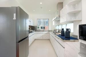 Una cocina grande con gabinetes blancos y un refrigerador. en Capitel Rama 4, en Bangkok