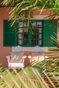 um quarto com 2 cadeiras e janelas com persianas verdes em Pousada Vila Campeche em Florianópolis