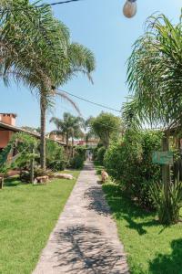 a path through a resort with palm trees and grass at Pousada Vila Campeche in Florianópolis