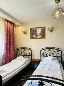 1 dormitorio con 2 camas y lámpara de araña en Pokoje noclegowe KASZTEL - Łowisko en Łowisko