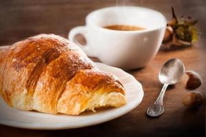 ein Teller mit einem Croissant und einer Tasse Kaffee in der Unterkunft Opera Foresteria in Rovato