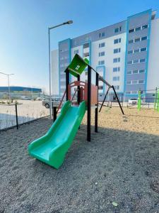 a playground with a green slide in the sand at Apartmán Twins Blue blízko centra in Michalovce