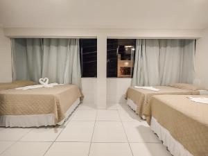 Pousada do Alemão في ماراغوغي: سريرين في غرفة ذات أرضيات بيضاء ونوافذ