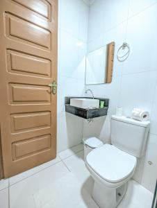 a white bathroom with a toilet and a sink at Pousada do Alemão in Maragogi
