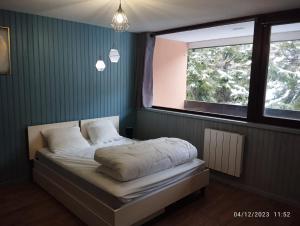a bed in a room with two windows at Proches des pistes F2 36m2 4-6 pers 2 étoiles in Besse-et-Saint-Anastaise