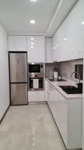 uma cozinha com armários brancos e um frigorífico de aço inoxidável em Up Sal em Aveiro