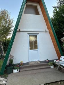 mały biały dom z białymi drzwiami w obiekcie Bungalov Dunja w mieście Podgorica