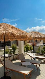 a group of lounge chairs under a straw umbrella at B&B Barone Liberty & Luxury SPA in Gallipoli
