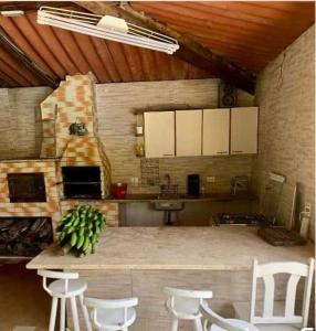 Il comprend une cuisine équipée d'un comptoir avec des chaises et une cuisinière. dans l'établissement Chácara Recanto dos pássaros, à Bairro das Rosas