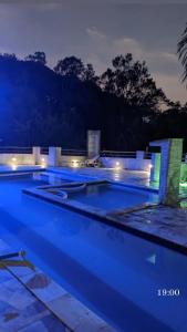- une grande piscine avec des lumières bleues la nuit dans l'établissement Chácara Recanto dos pássaros, à Bairro das Rosas
