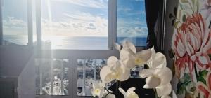 a window with a view of the ocean with white flowers at Luxury ocean view 1 bedroom in Playa de las Americas
