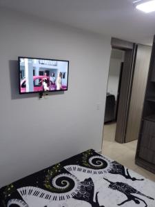 a flat screen tv hanging on a wall in a bedroom at OroNegroApartaHoteles Espectacular Apartaestudio Amoblado Armenia, Quindio in Armenia