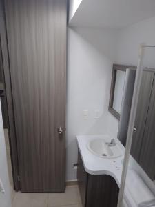 a bathroom with a sink and a wooden door at OroNegroApartaHoteles Espectacular Apartaestudio Amoblado Armenia, Quindio in Armenia