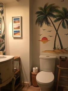 La salle de bains est pourvue de toilettes et d'une fresque murale de palmiers. dans l'établissement Quiet cozy apartment with A/C, backyard, Netflix, à Montréal