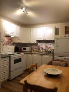 une cuisine avec des placards blancs et une table en bois dans l'établissement Quiet cozy apartment with A/C, backyard, Netflix, à Montréal