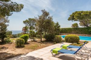 a swimming pool with two lounge chairs and the ocean at Villa Ponent Galdana - Cala Galdana in Cala Galdana