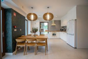a kitchen with a wooden table and some lights at Gátőr Villa in Mőcsény