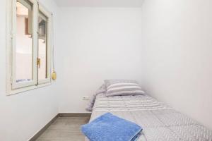 ein Bett in einem weißen Zimmer mit einem Fenster in der Unterkunft Acogedor alojamiento a pocos metros de la playa in Santa Pola