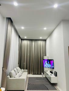 a living room with a white couch and a tv at HomeHug@ChiangRai in Chiang Rai