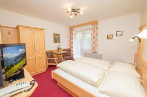 a hotel room with a bed and a television at Pension Bergblick in Kaprun