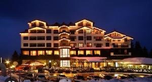 a large building with a parking lot in front of it at Private Apartments in Hotel Snezhanka in Pamporovo