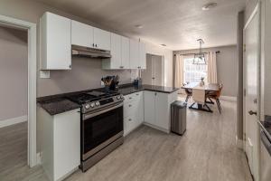 a kitchen with white cabinets and a stove and a table at Bungalow Oasis in Concord