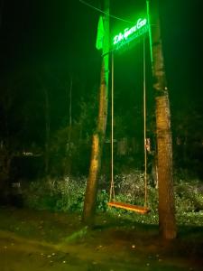 un'insegna al neon appesa tra due alberi di notte di Dva Braty eco a Podobovets