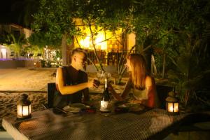 um homem e uma mulher sentados à mesa com uma garrafa de vinho em Blue Ocean Resort em Netolpitiya