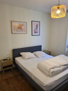 Un dormitorio con una cama con sábanas blancas y una lámpara de araña. en Le Déodatien, en Saint-Dié-des-Vosges