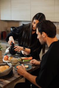 Eine Frau und ein Mann bereiten Essen in einer Küche vor. in der Unterkunft Apanemia Inn Studio in Lofou