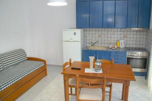 a kitchen with blue cabinets and a table and a couch at Istira in Possidi
